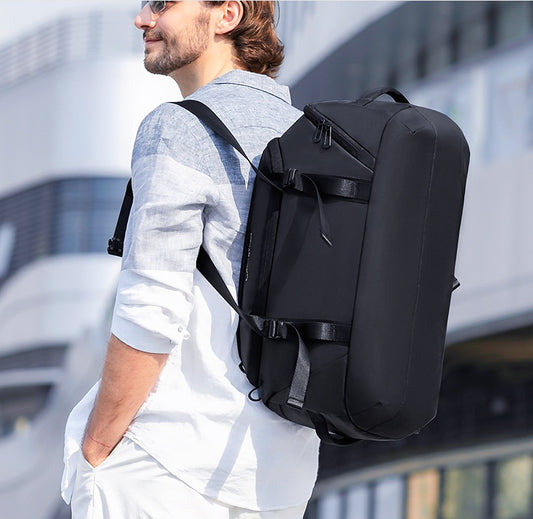 Black convertible duffel worn as a backpack by a man outdoors