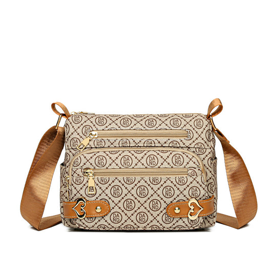 Cream monogram-pattern crossbody bag with tan strap and gold zips, front view