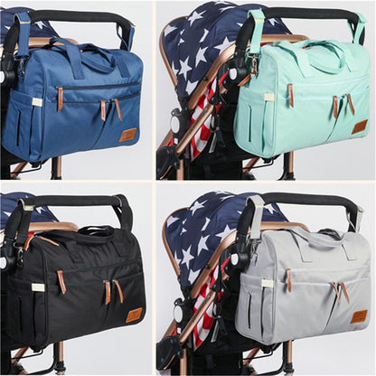 The diaper bag shown clipped to a stroller handle in navy, mint, black and grey