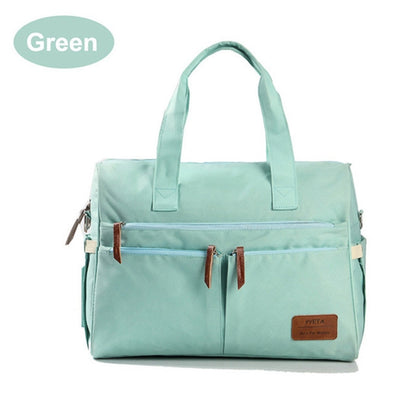 Mint green diaper bag with front zip pockets and tan leather tabs