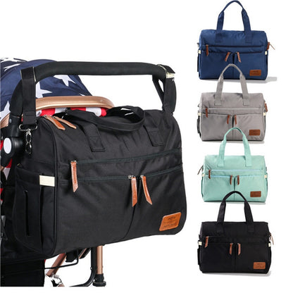 Black diaper bag tote attached to a stroller handle