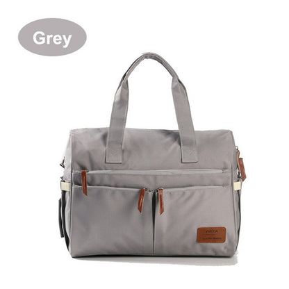 Grey diaper bag with front zip pockets and tan leather tabs
