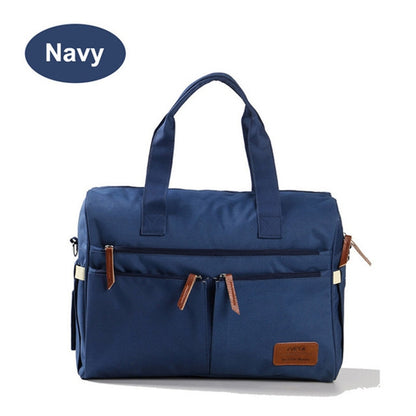 Navy diaper bag with front zip pockets and tan leather tabs