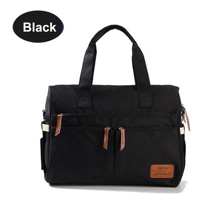Black diaper bag with front zip pockets and tan leather tabs