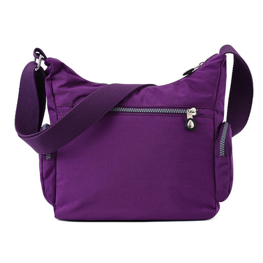Back of the purple nylon crossbody bag with a single zip pocket
